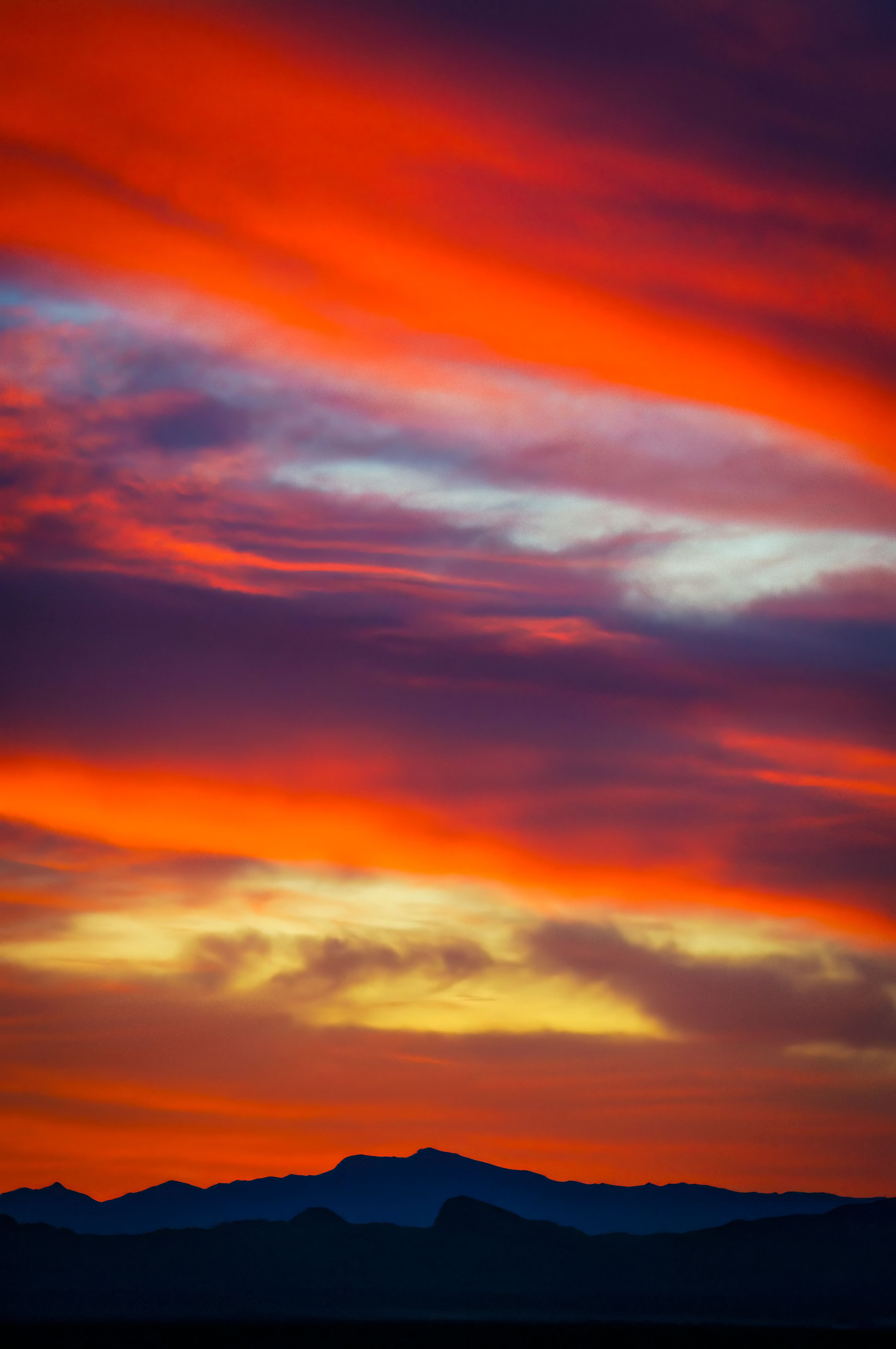 Vivid red and orange sunset sky over silhouetted desert mountains in the Mojave.