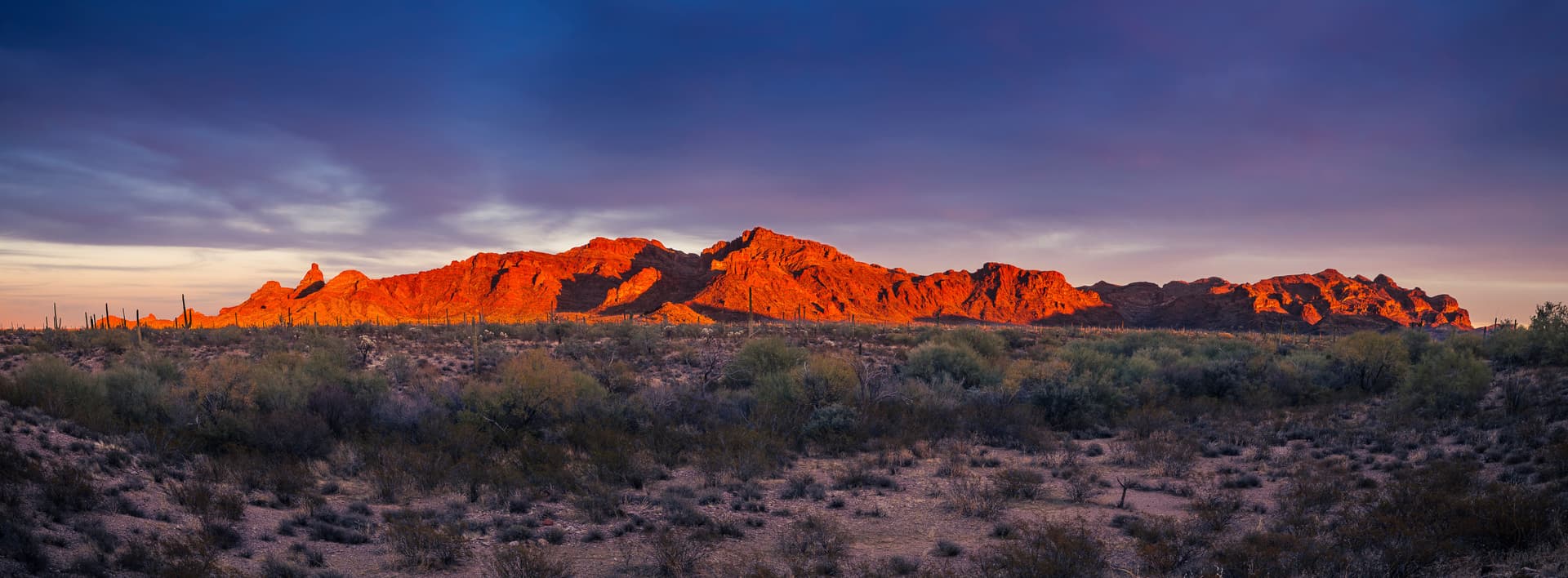 Fine art landscape photograph of Arizona desert mountains glowing red-orange at sunset with saguaro cacti and Sonoran Desert landscape