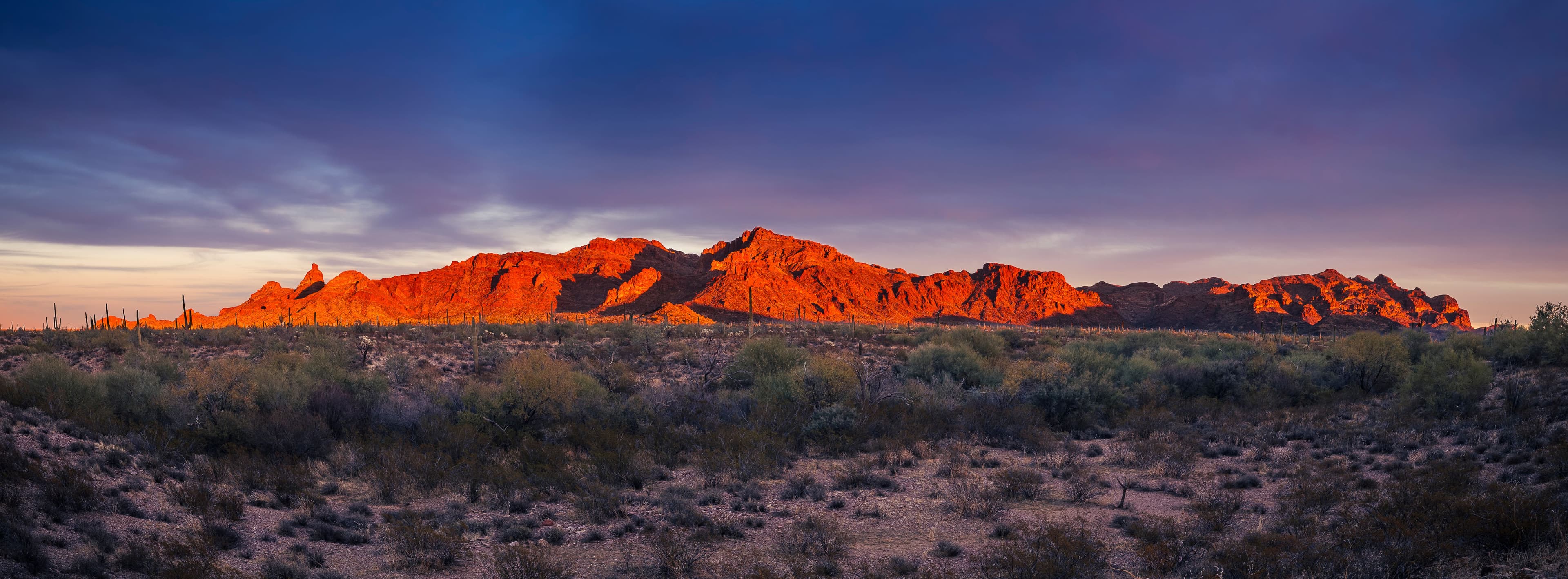 Fine art landscape photograph of Arizona desert mountains glowing red-orange at sunset with saguaro cacti and Sonoran Desert landscape