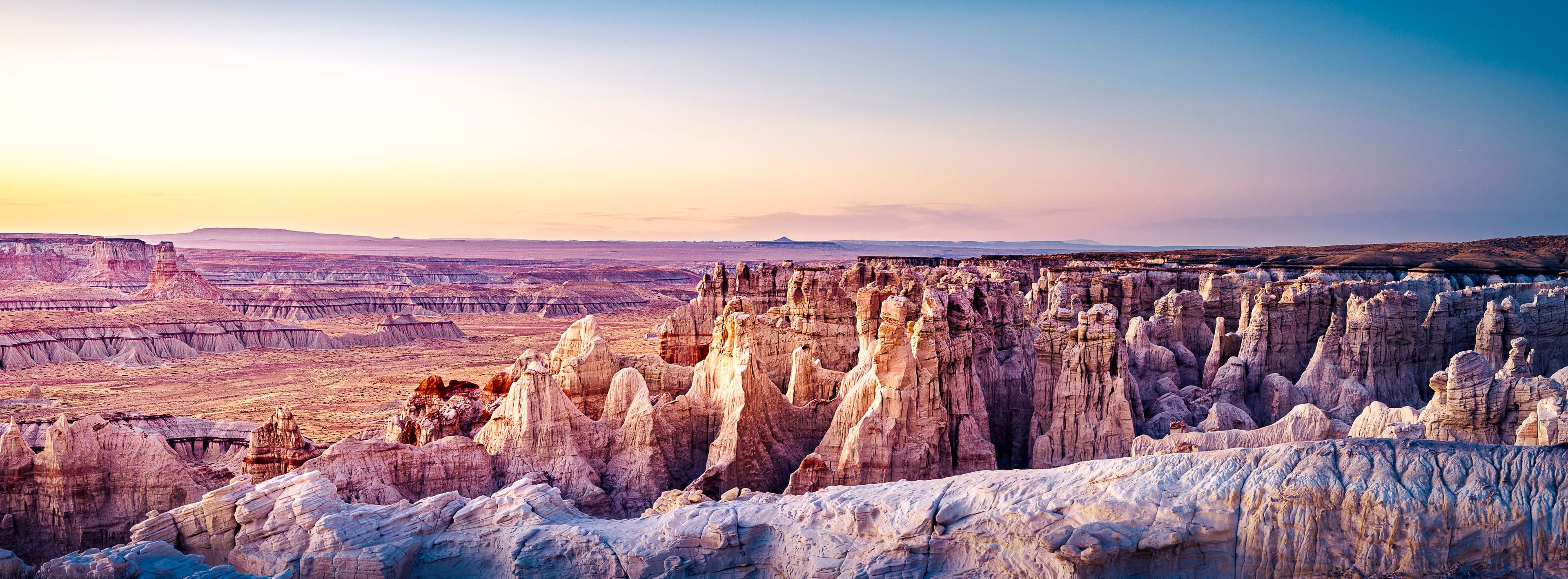 Cathedral-like desert rock formations glowing at sunrise under a lavender sky, evoking a sense of ancient stillness and grandeur